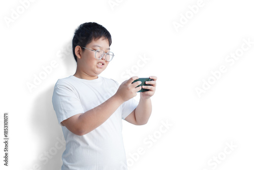 A young Asian man is enjoying playing games on his smartphone against a white background.