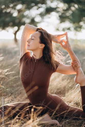 A woman performs a calm yoga pose in nature, enjoying balance, flexibility, and the soft glow of sunlight.