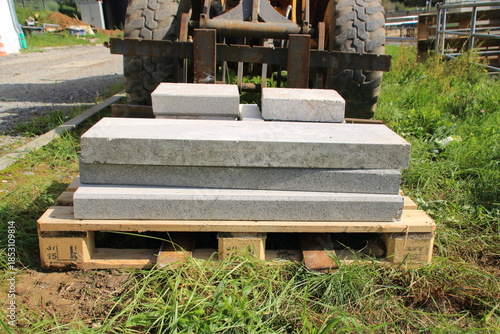 Betonplatten auf einer Palette werden mit einem Radlader transportiert