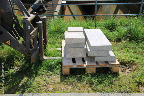 Betonplatten auf einer Palette werden mit einem Radlader transportiert