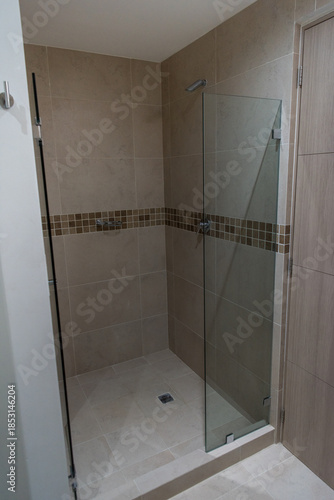 Modern walk-in shower with glass partition and decorative mosaic tile accent