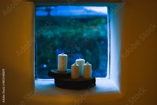 White candles on wooden coasters in a small window niche