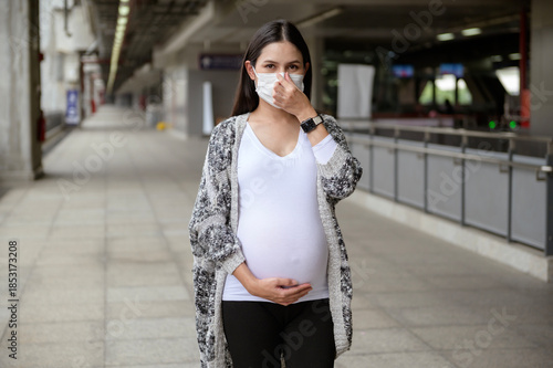 Pregnant woman wearing protective mask outdoors, health and maternity concept.