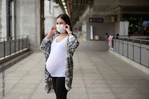 Pregnant woman wearing protective mask outdoors, health and maternity concept.