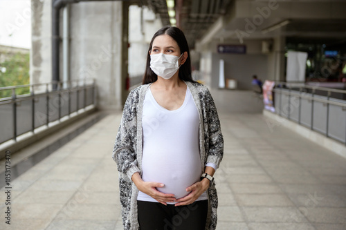 Pregnant woman wearing protective mask outdoors, health and maternity concept.