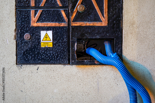 Electrical junction box in building facade with blue conduit urban technical infrastructure detail
