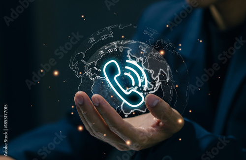 A glowing phone icon over a digital globe in a professional hand represents global communication, call center support, customer service, international business, and telecom technology.
