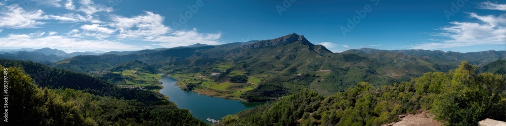 Obraz premium Panoramic view of lush green valley and majestic mountain under blue sky