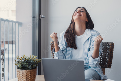 Funny euphoric young caucasian woman celebrating winning or getting ecommerce shopping offer on computer laptop. Excited happy girl winner looking at notebook celebrating success