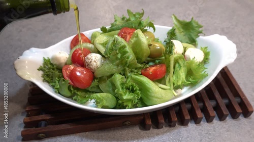 Stockholm, Sweden A cook drizzles olive oil and balsamic vinegar on green salad.