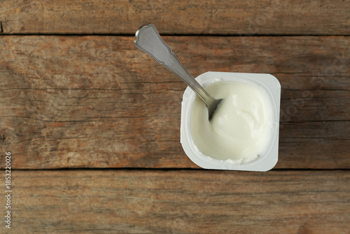 Yogurt in a Container on a Wooden Table With a Spoon