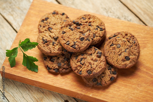 Freshly Baked Chocolate Chip Cookies on a Wooden Board With Green Garnish