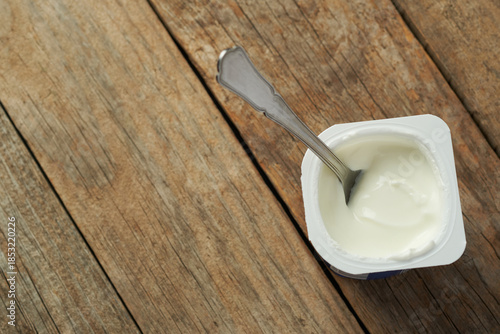 Yogurt in a Container on a Wooden Table With a Spoon