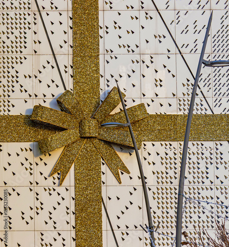 Shiny sparkling gold bow ornament outside on building wall