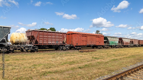 Fotografi Freight cars on tracks against a cloudy sky, railway infrastructure, transport, and industry
