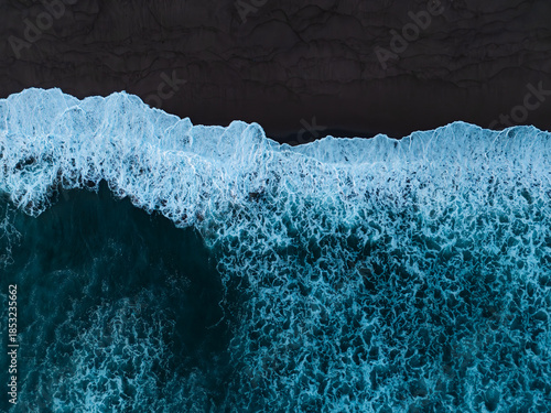 Tableau sur toile Strong waves of ocean reaching black sandy beach at sunrise