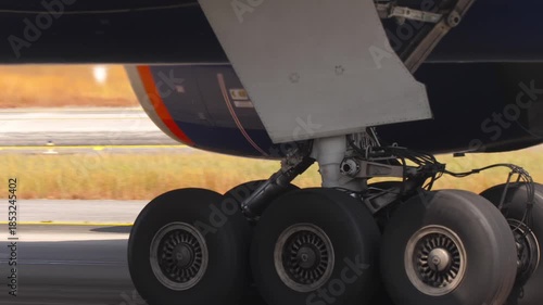 Close-up view of a commercial aircraft engine and landing gear on the tarmac. Themes of travel, transportation, maintenance, and modern aviation