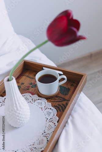  Romantic breakfast in bed with coffee and red tulip on wooden tray