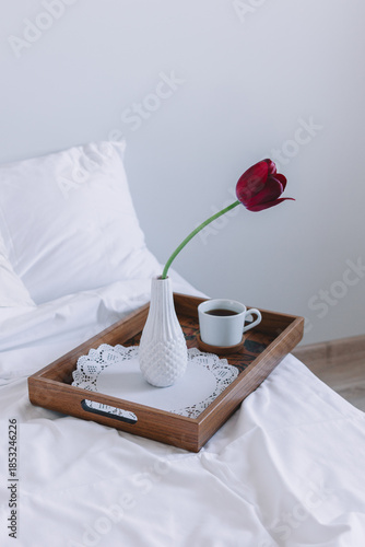  Romantic breakfast in bed with coffee and red tulip on wooden tray