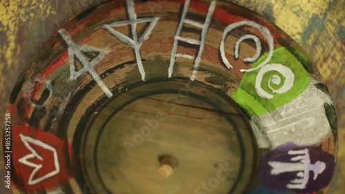 An old wooden wheel with strange signs and symbols is spinning, loop