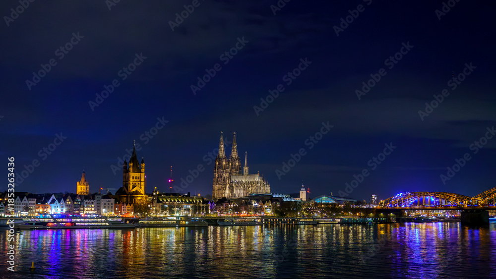 Obraz premium Cologne city skyline panorama at night, Rhine river with illuminated Cologne Cathedral, Great St. Martin Church and Hohenzollern Bridge, Germany
