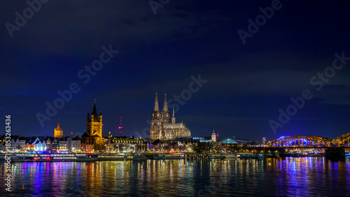 Cologne city skyline panorama at night, Rhine river with illuminated Cologne Cathedral, Great St. Martin Church and Hohenzollern Bridge, Germany