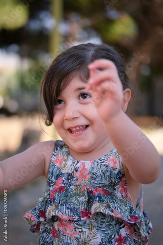 Cute toddler girl laughing and playing in a summer park.
