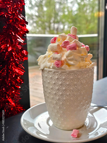 Cup of hot chocolate with whipped cream and candy canes on the table