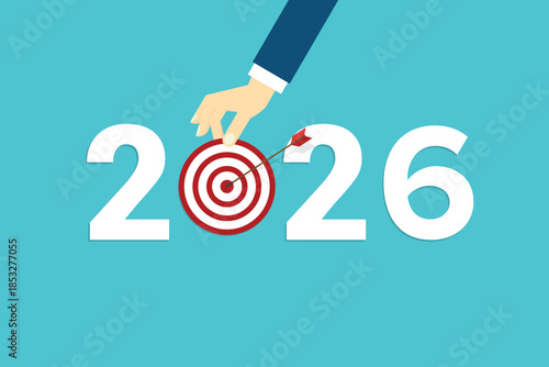 Human hand holding business target for a business year 2026. Red arrow hits target center.	
