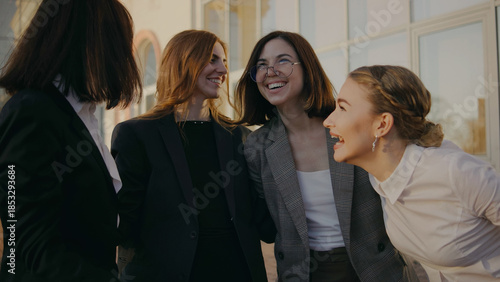 Four women gather outdoors for a fun moment while chatting and laughing during a sunny afternoon setting