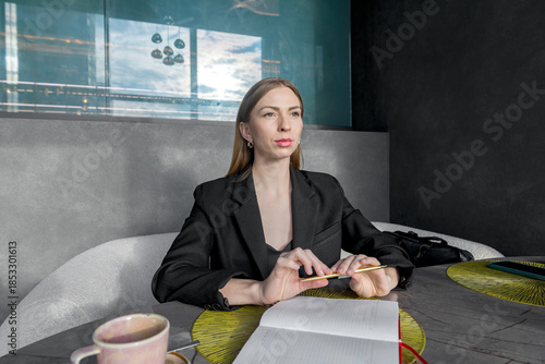 A girl sits at a table with a thoughtful face over a sketchpad.