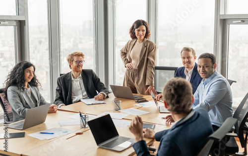 Fotografie A group of diverse business professionals are seated around a large conference table in a modern office space