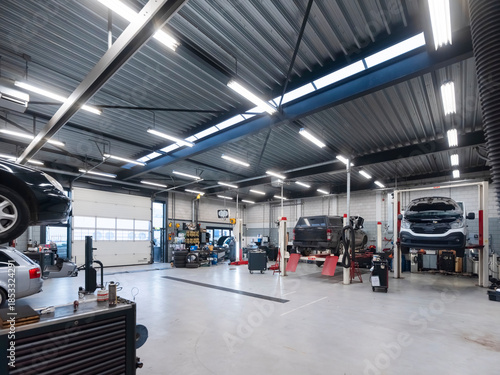 Spacious automotive workshop interior featuring natural skylight illumination with vehicles on lifts and organized service areas