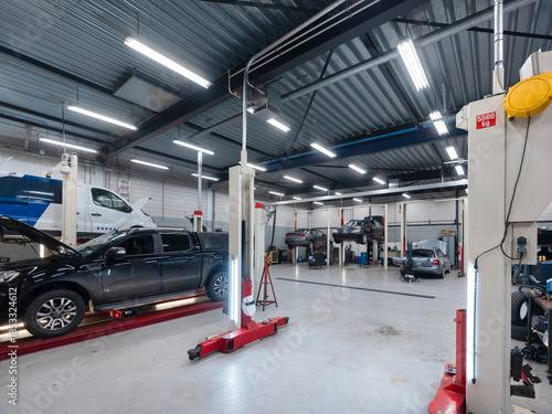 Automotive workshop interior showing pickup truck on hydraulic lift with multiple service bays and professional equipment