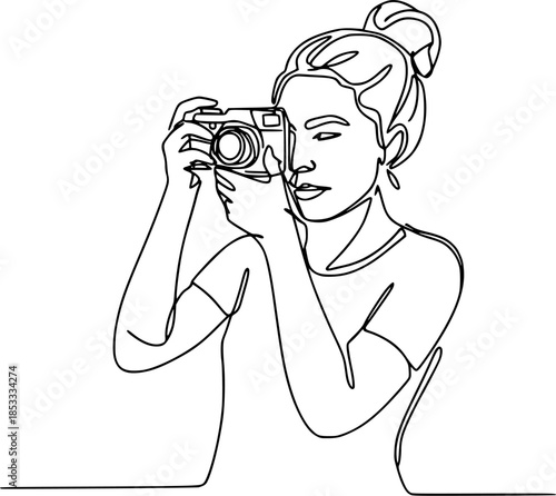 A professional young woman photographer holding a digital camera with a high-quality lens looks through the equipment to take a creative photo shot in a studio