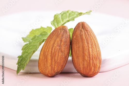 Whole Almonds with Fresh Green Leaves on Pink Background