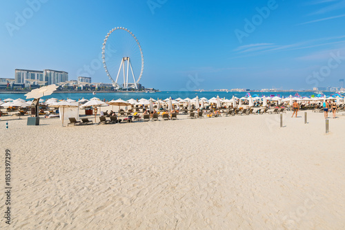Obraz na płótnie Visitors enjoy the sandy Jumeirah Beach, or JBR beach along the Persian Gulf with the Ain Dubai Ferris wheel behind, in Dubai, United Arab Emirates