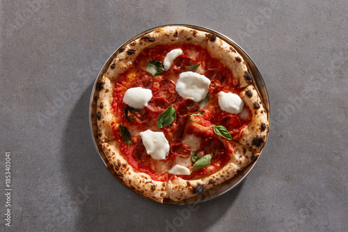 Authentic Neapolitan pizza with fresh mozzarella, pepperoni and basil on gray background