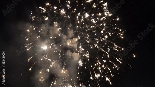 Brilliant white and gold fireworks exploding spectacularly against the dark night sky during a celebration