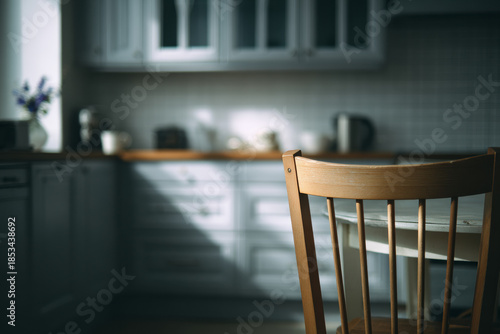A wooden chair lit by soft light in a quiet kitchen, capturing a paused domestic moment without people.