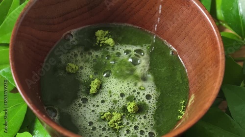 Process making matcha green tea. Mixing matcha tea with whisk in wooden bowl. Healthy matcha drinks	