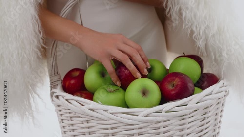 A woman in the studio with a basket of green and red apples