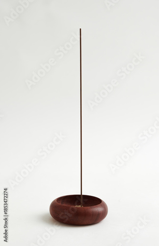 Minimalist wooden incense holder with incense stick on white background