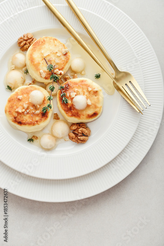 cottage cheese pancakes, syrniki, curd fritters served with pear balls, walnut and honey