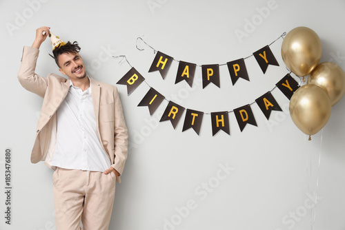 Happy young man celebrating Birthday on light background