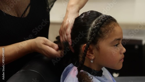 Hairdresser styling a young girl's braids with hair extensions in a salon