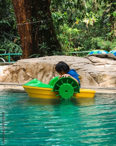 Little girl on a mini boat floating in the wate at a water park.