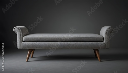 A minimalist gray sofa with wooden legs standing alone in a dimly lit room viewed from the front