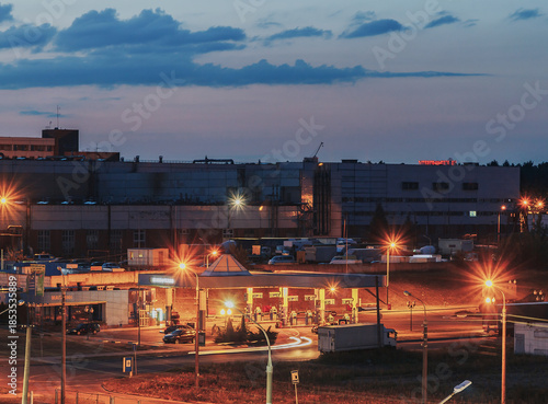 A gas station with several customers under a clear night sky. Gas station and convenience store at night