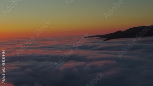 Aerial footage above the clouds of a sunset. Descending into the cloud ceiling